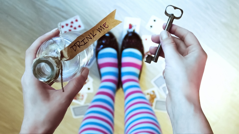 Alice in wonderland. Background. A key and a potion in hands against a floor