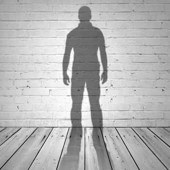 Shadow of a man on white brick wall and wooden floor